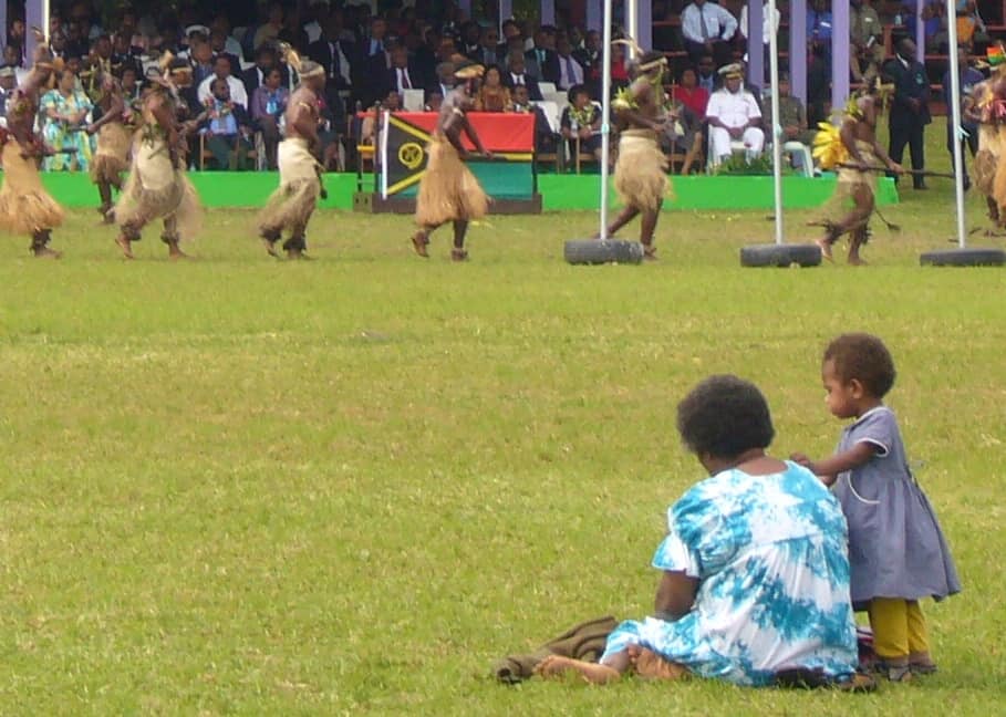 Woman and child watch men from the sidelines.