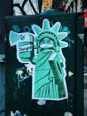 Drawing of the Statue of Liberty in a mask, holding disinfectant and gloves.