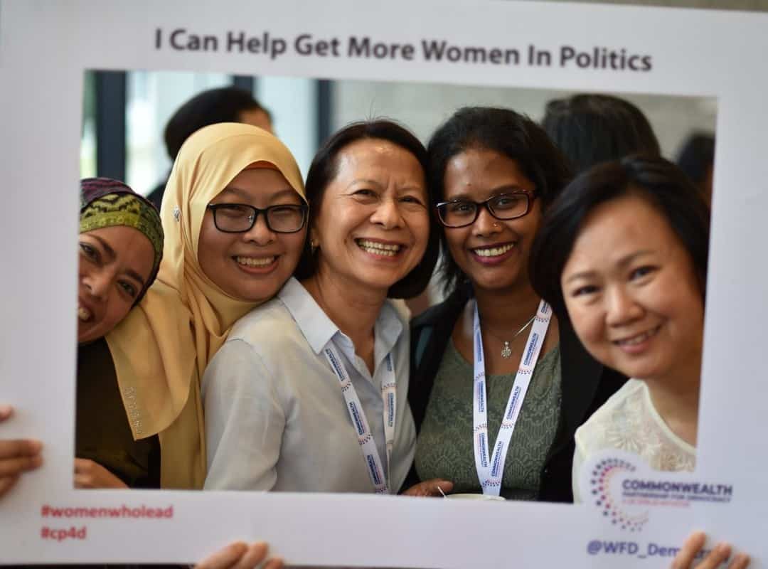 Sign with group of women smiling, reading