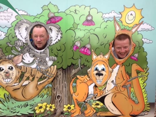 Two people's heads in a scenery backdrop of kangaroos and koalas