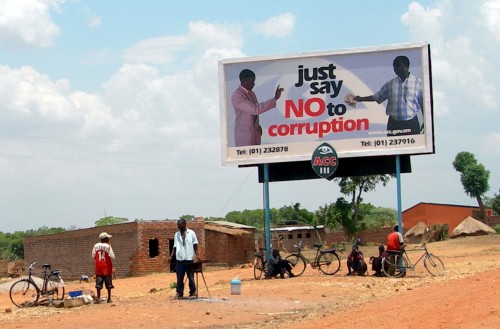 People standing below a sign reading "just say no to corruption"