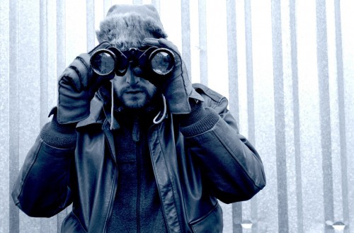 A person with binoculars against an icy backdrop