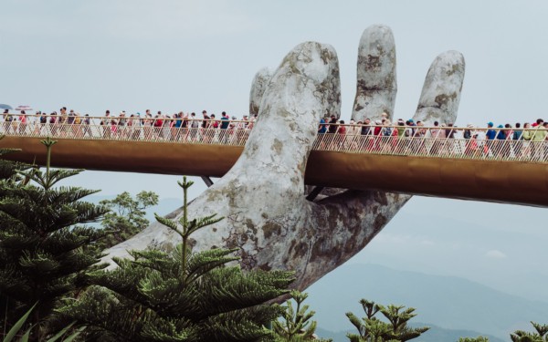 A hand holding up a bridge filled with people