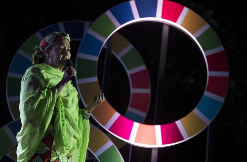 Woman speaking against backdrop of UN Sustainable Development Goals colours