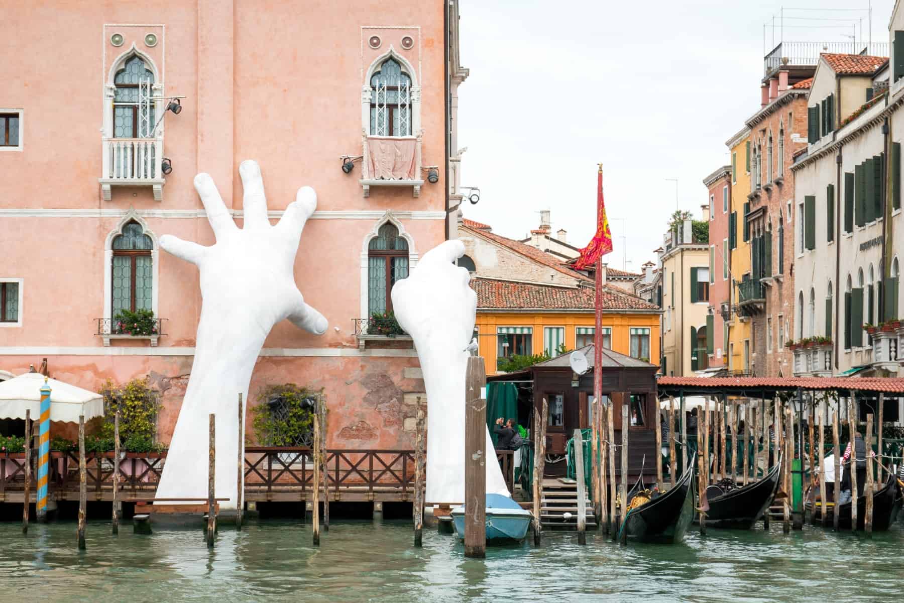A pair of hands reaching up the side of a building