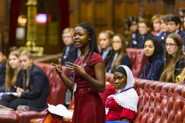 A woman speaking in House of Lords to an audience.
