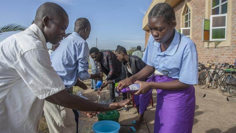 People spraying water and soap on the hands of others