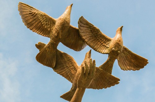 Statue of three birds flying, with a hand catching one
