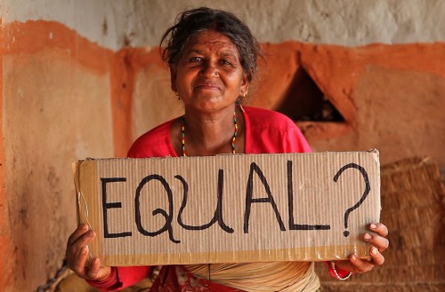 A woman holding a sign saying "Equal?"