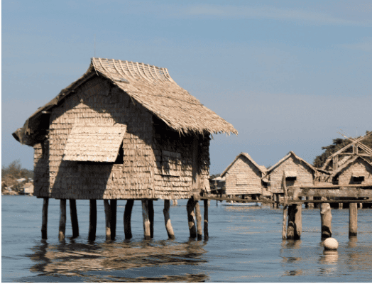 House on with a thatched roof on stilts in water